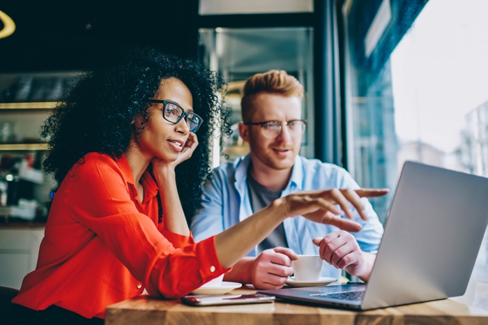 A man and a woman sat side by side looking at a laptop