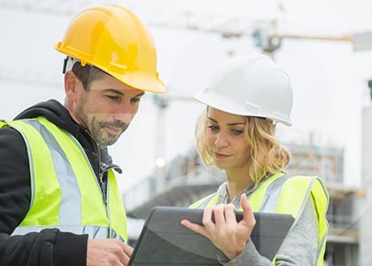 Male and female builders on a construction site looking at a tablet