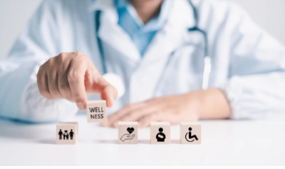 Healthcare professional placing a wooden block labelled Wellness beside icons representing family, wellbeing and accessibility.